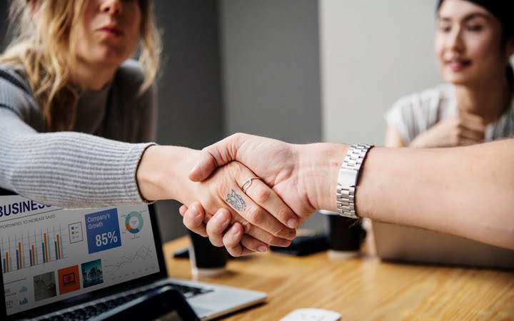 People shaking hands over laptop.